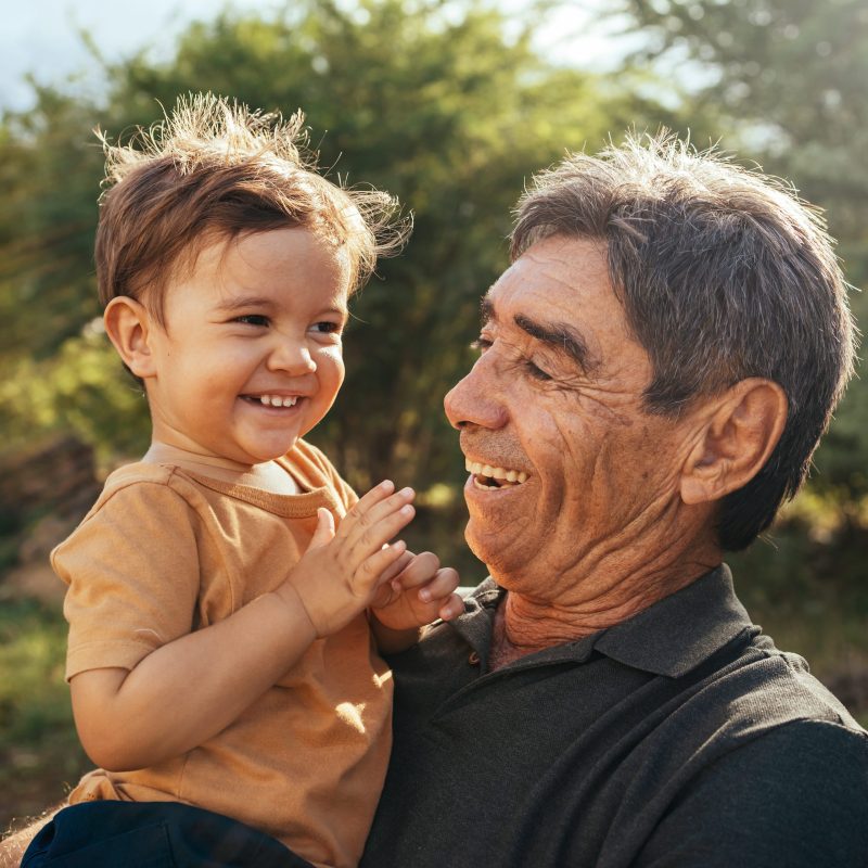 Playful grandfather spending time with his grandson in park on sunny day Playful grandfather spending time with his grandson in park on sunny day