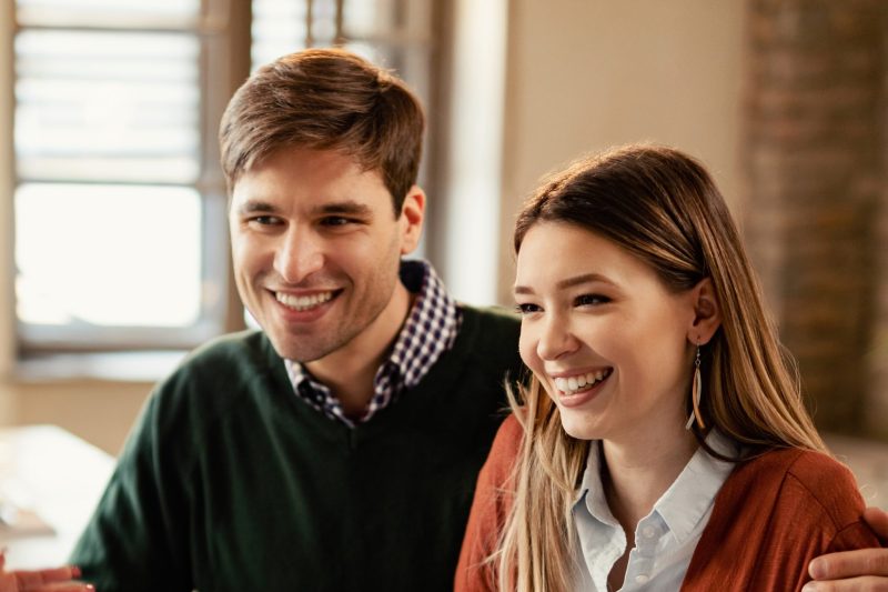 Young happy couple signing a contract while being on a meeting with insurance agent in the office.