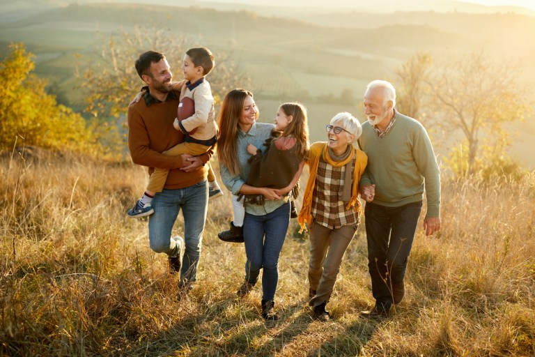 Happy multi-generation family talking while taking a walk on a hill. generational family walking considering a donor-advised fund vs. private foundation